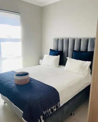 a bedroom with a large bed with a blue headboard at Ladybug ladybug in Midrand