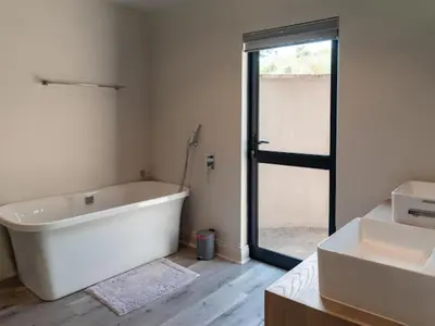 a bathroom with a bath tub and two sinks at Whiskey Creek in Dullstroom
