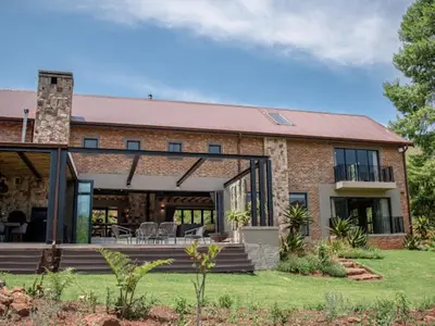 a brick house with a deck and patio at Whiskey Creek in Dullstroom