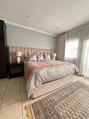 a bedroom with a large bed and a rug at Bluestream Villas in Pretoria