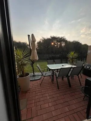 a patio with a table and chairs and an umbrella at Bluestream Villas in Pretoria