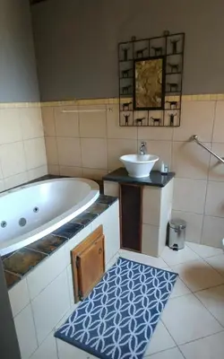 a bathroom with a tub and a sink at Sky Lodge in Hartbeespoort