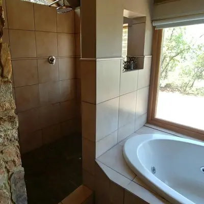 a bathroom with a tub and a sink and a window at Sky Lodge in Hartbeespoort