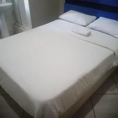a large white bed with white sheets and pillows at Ebony Guest House in Pretoria