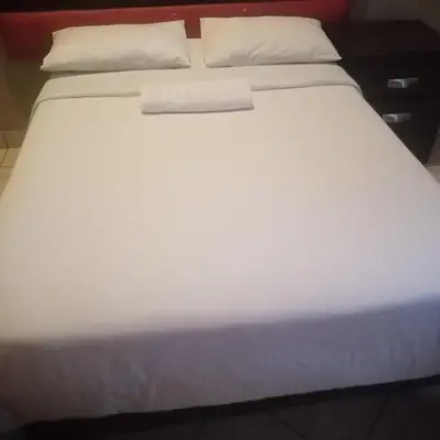 a large white bed with white sheets and pillows at Ebony Guest House in Pretoria