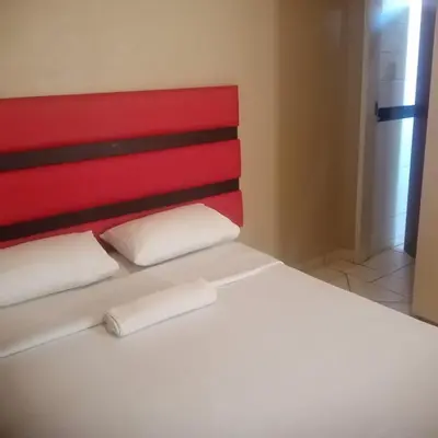 a bed with two white pillows and a red headboard at Ebony Guest House in Pretoria