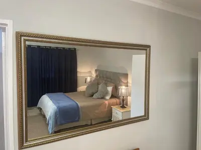 a mirror on a wall with a bed in a room at Pringle Cottage in Benoni