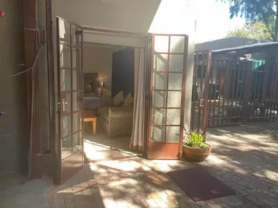 an open door to a patio with a couch at Pringle Cottage in Benoni