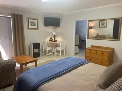 a bedroom with a bed and a table with a chair at Pringle Cottage in Benoni