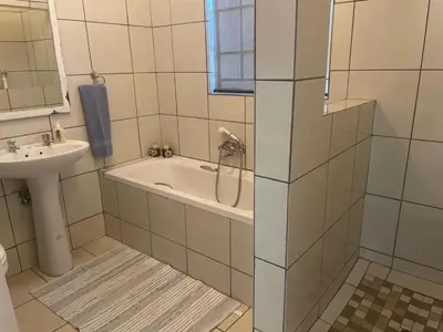 a bathroom with a bath tub and a sink at Pringle Cottage in Benoni