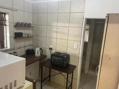 a small kitchen with a table with a radio on it at Pringle Cottage in Benoni