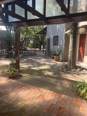 a courtyard with a building with a fence and plants at Pringle Cottage in Benoni