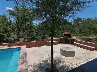 a swimming pool with a tree and a grill at Sunset on Kingfisher in Marloth Park