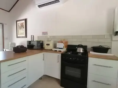 a kitchen with white cabinets and a black stove at Sunset on Kingfisher in Marloth Park