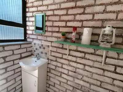 a bathroom with a sink and a brick wall at Sunset on Kingfisher in Marloth Park