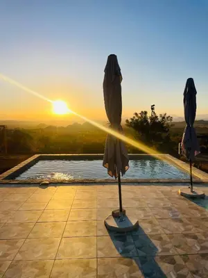 two umbrellas in front of a pool with the sunset at Makgobelo Lodge-The Glass House- Solar powered in Ga-Mokalapa