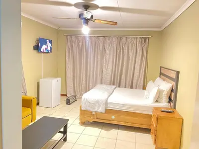 a bedroom with a bed and a ceiling fan at c and c guest house pretoria north in Pretoria