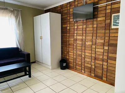 a room with a black chair and a brick wall at c and c guest house pretoria north in Pretoria