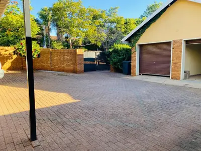a brick driveway in front of a house with a garage at c and c guest house pretoria north in Pretoria