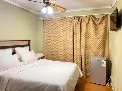 a bedroom with a white bed and a window at c and c guest house pretoria north in Pretoria