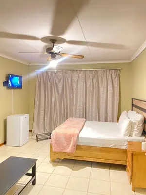 a bedroom with a bed and a ceiling fan at c and c guest house pretoria north in Pretoria