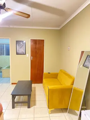 a living room with a yellow couch and a table at c and c guest house pretoria north in Pretoria