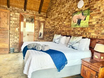 a bedroom with a large bed in a brick wall at Zaganaga Kruger Lodge in Marloth Park