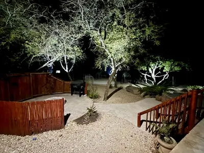 a garden at night with a fence and a tree at Zaganaga Kruger Lodge in Marloth Park