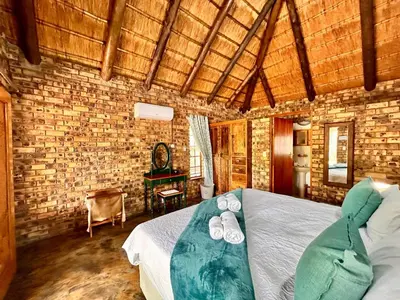 a bedroom with a bed with slippers on it at Zaganaga Kruger Lodge in Marloth Park