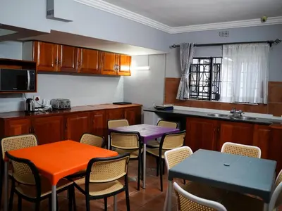 a kitchen with two tables and chairs in it at Aqua Guest House in Sandown