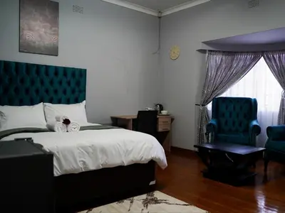 a bedroom with a bed and a blue chair at Aqua Guest House in Sandown