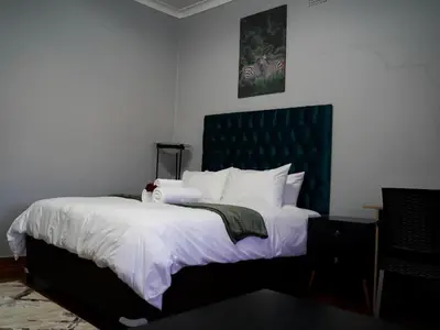 a bedroom with a large bed with a green headboard at Aqua Guest House in Sandown