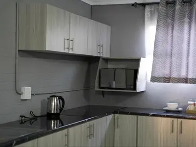 a kitchen with white cabinets and a microwave at Aqua Guest House in Sandown