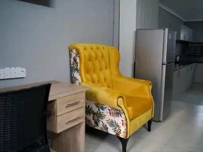 a yellow chair in a kitchen with a desk and a refrigerator at Aqua Guest House in Sandown