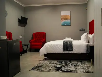 a bedroom with a bed and a red chair at Aqua Guest House in Sandown