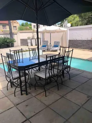 a table and chairs with an umbrella next to a pool at Red Cascade - Luxury 4 bedrooms -solar and aircons in Hartbeespoort