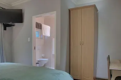 a bedroom with a bed and a wooden cabinet at ilanda Guest House in White River