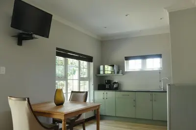 a kitchen with a wooden table and a television on the wall at ilanda Guest House in White River