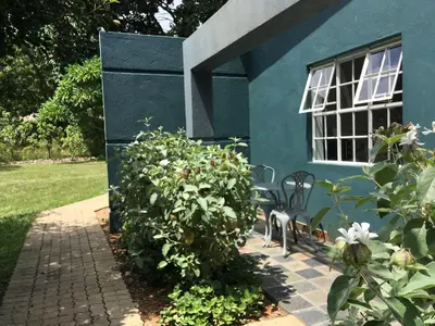 a blue house with a bench in front of a bush at ilanda Guest House in White River