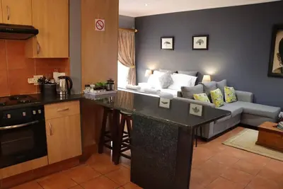 a kitchen and living room with a couch in the background at Studio in Lynnwood garden estate in Pretoria