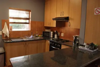 a kitchen with wooden cabinets and a black counter top at Studio in Lynnwood garden estate in Pretoria