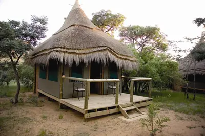 a small hut with chairs and a thatched roof at Wildside Safari Camp in Golders Green