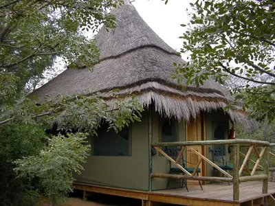 a hut with a thatched roof with a deck at Wildside Safari Camp in Golders Green