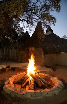 a fire burns in a circle in front of a building at Wildside Safari Camp in Golders Green