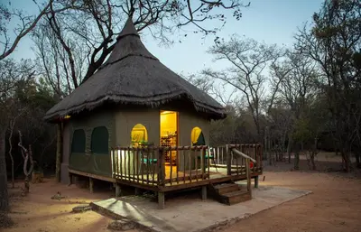 a small hut with a thatched roof and a deck at Wildside Safari Camp in Golders Green