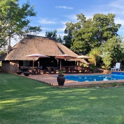 a hut with a pool and tables and umbrellas at Clartal's Place in Isidule