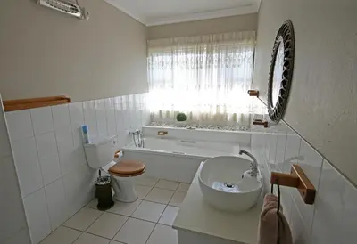a white bathroom with a toilet and a sink at Clartal's Place in Isidule