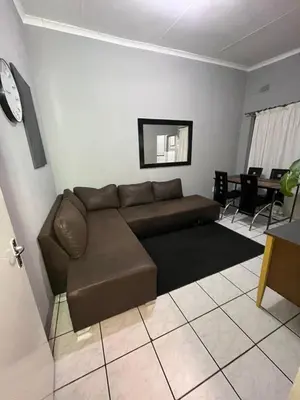 a living room with a brown couch and a table at Kiewiets Cradle Guest House in Pretoria
