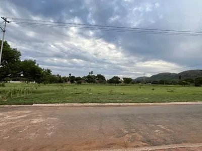 an empty road with a field of grass and mountains at Kiewiets Cradle Guest House in Pretoria