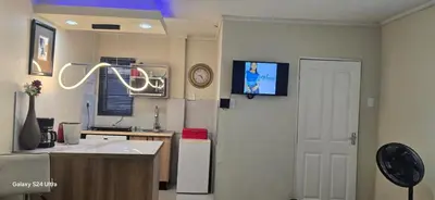 a kitchen with a sink and a door with a clock at Okoli's Place in Sandown
